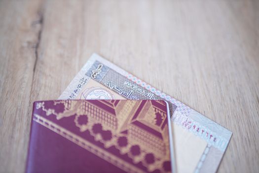 Picture of a Kuwait Quarter Dinar -with the words Bank of Kuwait and the numbers 1-fourth in Arabic- Partially Inside a Sweden Passport