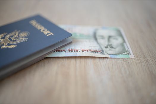Picture of a 2000 Colombian Pesos Bill that reads Two Thousand Pesos, and it is Partially Inside a United States of America Passport