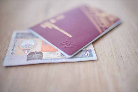Picture of a Kuwait Quarter Dinar -with the numbers 1-fourth in Arab- Partially Inside a blurry Sweden Passport