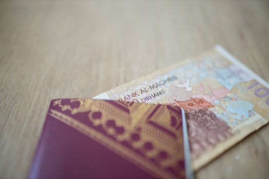 Picture of a 100 Moroccan Dirhams Bill Partially Inside a blurry Sweden Passport