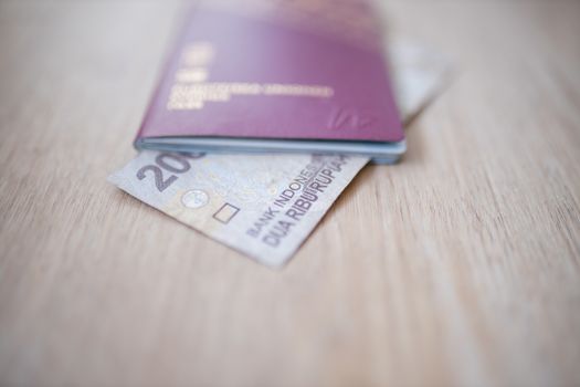 Picture of a 2000 Indonesian Rupees Bill -with the words Indonesia Bank and Two Thousand Rupees in Indonesian- partially Inside a blurry Sweden Passport