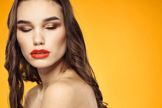 beautiful brunette red lips bare shoulders skin care yellow background. High quality photo