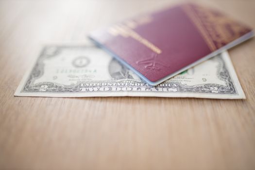 Two-Dollar Bill Partially Inside a Blurry Sweden Passport on a Wooden Table