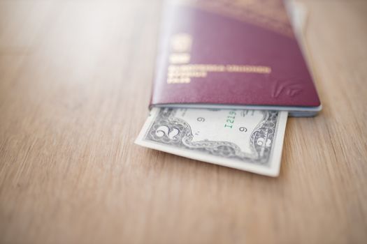 Two-Dollar Bill Partially Inside a Blurry Sweden Passport on a Wooden Table