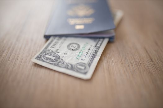 Picture of a One-Dollar Bill Partially inside a United States of America Passport on a Wooden Table