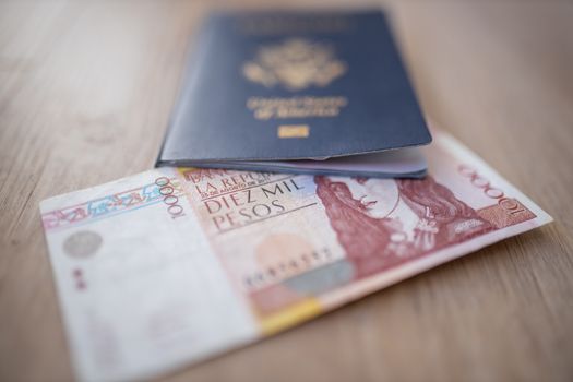 United States of America Passport with half a 10.000 Colombian Pesos Bill Inside, showing the Face of Policarpa Salavarrieta