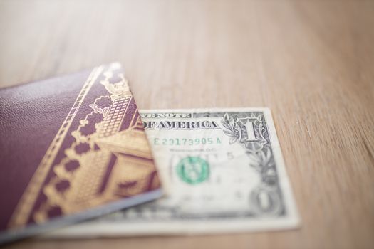 Half a One-Dollar Bill Under a Sweden Passport on a Wooden Table