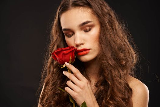 woman with a red rose on a dark background long hair makeup red lips. High quality photo