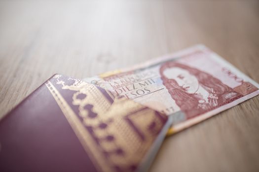 Picture of a Swedish Passport with half a 10.000 Colombian Pesos Bill Inside, showing the Face of Policarpa Salavarrieta