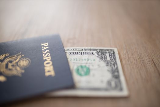 Picture of One-Dollar Bill Partially covered by a United States of America Passport on a Wooden Table