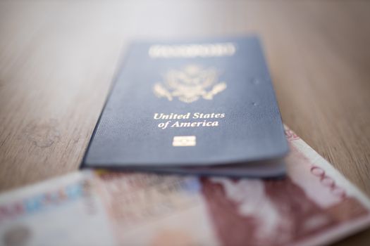 United States of America Passport with the corner of a blurry 10.000 Colombian Pesos Bill Inside