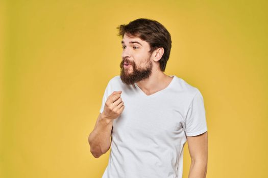 Man gesturing with hands emotions lifestyle white t-shirt yellow isolated background. High quality photo
