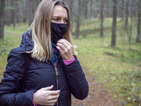 Beautiful european Women Wearing Protective Mask Outside Pretty young girl in medical black face mask in a forest. covid19 concept. modern reality. copy space. 2020, allergy. Autumn season. Copy space