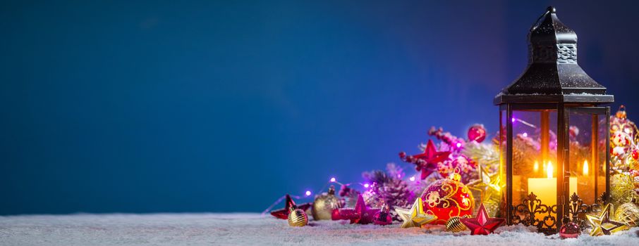 Christmas composition of lantern colorful ornaments balls stars candles and fir tree branches on snow