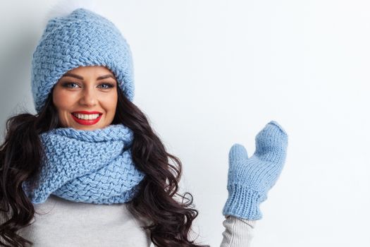 Smiling woman wearing blue knitted winter hat, scarf and mittens