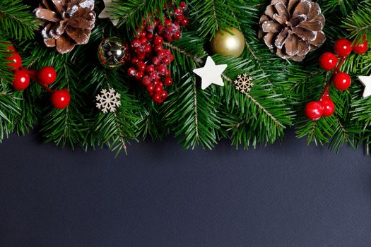 Natural fir Christmas tree border frame with decor on black, copy space for text