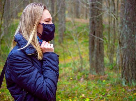 Beautiful european Women Wearing Protective Mask Outside Pretty young girl in medical black face mask in a forest. covid19 concept. modern reality. copy space. 2020, allergy. Autumn season. Copy space