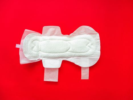 Feminine sanitary pads for menstrual protection are placed on a red background.