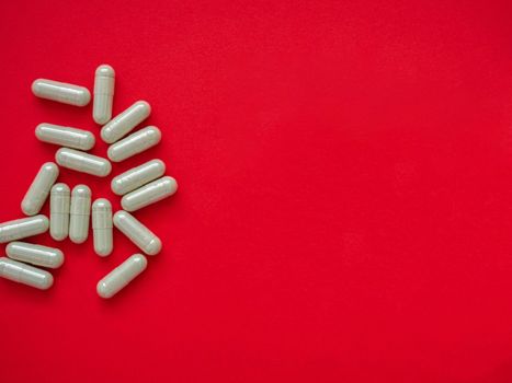 Gray pills for the treatment of body disorders are arranged on a red background