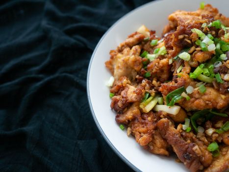 Thai food Stir fry chicken and chili in oil. Local Thai food can be eaten in a restaurant. The main ingredient uses fried chicken with chili on, black background.