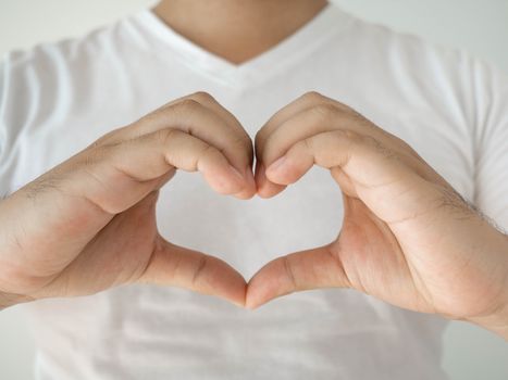 The man in the white shirt put his fingers together in a heart shape on his chest. Show love and charm With a white background