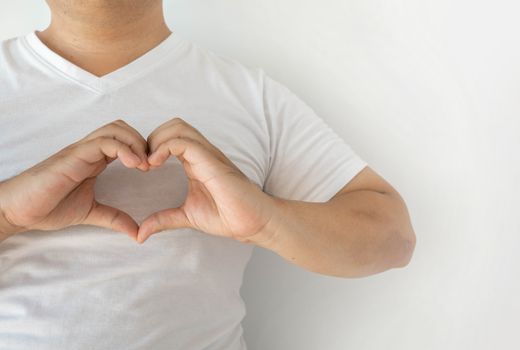 The man in the white shirt put his fingers together in a heart shape on his chest. Show love and charm With a white background