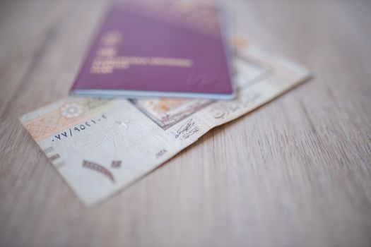 Picture of a Ten Saudi Riyals Bill -with the number 10 in Arabic- Partially Inside a blurry Sweden Passport