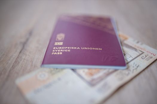 Picture of a Swedish Passport -with the words European Union Sweden Passport in Swedish- with a blurry Ten Saudi Riyals Bill Partially Inside