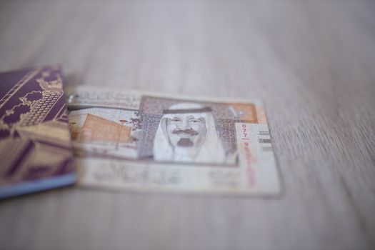 Picture of a Ten Saudi Riyals Bill -with the words Saudia Arabian Monetary Agency, and the number 10 in Arabic- Partially Inside a Sweden Passport