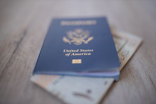 Picture of a United States of America Passport with a blurry Ten Saudi Riyals Bill Partially Inside