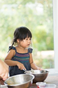 Asian little girl cooking something in kitchen