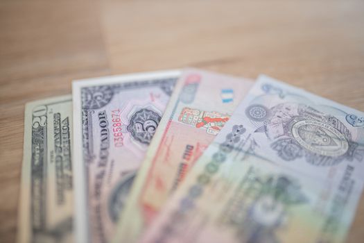 Up-Close Picture of a Twenty-Dollar bill, a Five Sucres bill, a Ten Quetzales bill, and a Five Lempiras Bill on a Wooden Table