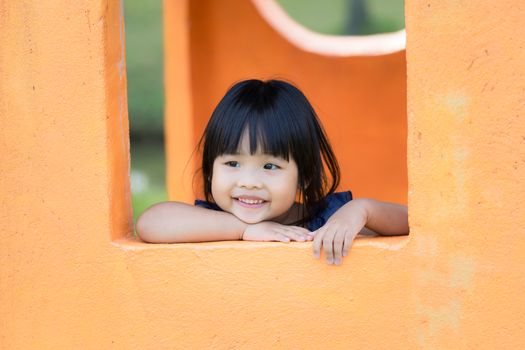 Asian little girl in the window enjoys playing in a children playground