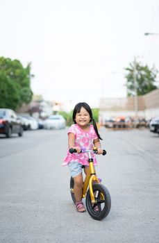 Little girl learns to riding balance bike on the road