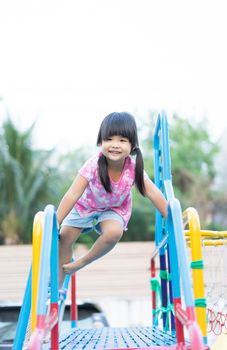 little girl having fun to play slider in the playground in summer time