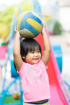 Asian little girl enjoys playing ball in a children playground