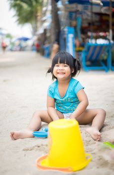 smiling little girl playing sand on the beach