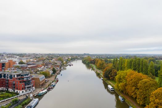 Aerial Landscape Picture Under a Cloudy sky and Over a River that Divides a Town and a Small Forest