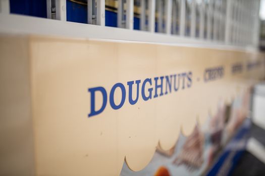 Landscape lateral view of the blue word Doughnuts on the signboard of an outdoor sweet snacks stand in London, UK