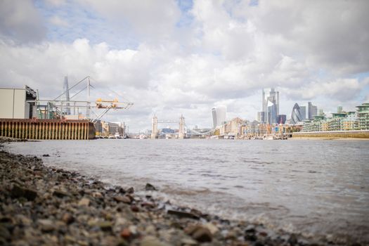 Landscape View of a Cityscape and the Tower Bridge from the Rocky Ground Alongside the River Thames in London, UK