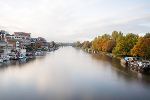 Aerial Landscape Picture Under a Cloudy sky and Over a River that Divides a Town and a Small Forest