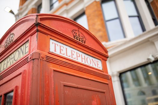 Landscape Close up view of the top of a classic London telephone booth with a blurry brick building with white columns as background