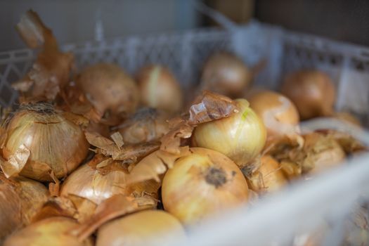 Picture of Fresh Brown Onions in a Blurry White Plastic Basket For Sale