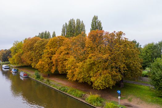 Aerial Landscape Picture of Orange and Green Trees Alongside The River and under a cloudy sky