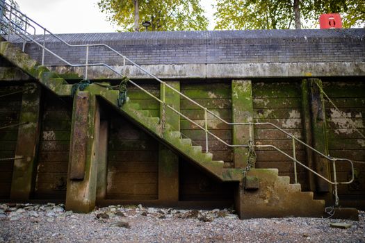 Landscape View of a Staircase alongside a Concrete Wall Partially Covered by Moss with a gray rocky ground at the bottom