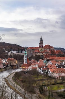 Beautiful aerial of Český Krumlov old town with the Cesky Krumlov castle and tower in background and Vltava river flowing around on a cloudy day, Czech Republic