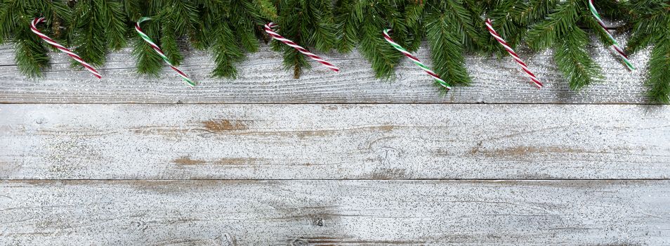 Border of Evergreen branches with candy cane ornaments for Christmas or New Year holiday background
