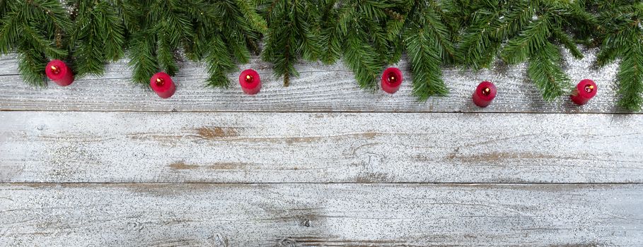 Border of Evergreen branches and burning red candle decorations for Christmas or New Year holiday background 