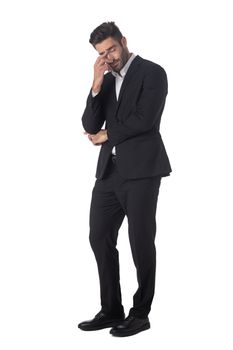Full length portrait of young handsome business man in black suit feeling stress or depression studio isolated on white background