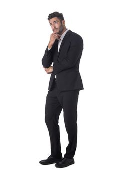 Full length portrait of young handsome business man in black suit thinking holding hand on chin studio isolated on white background